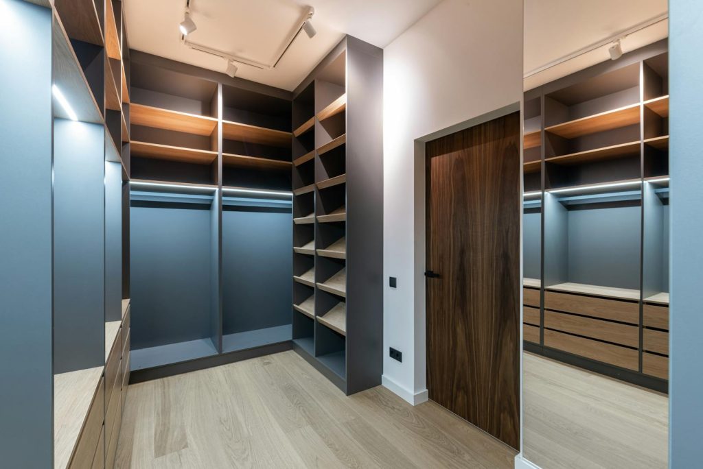 Modern walk-in wardrobe with wooden shelving and sleek design, featuring ample storage space and minimalist aesthetics